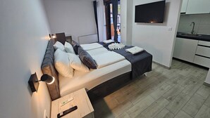 Une chambre d’hôtel moderne équipée d’un lit, d’une table de chevet, d’une télévision et d’une petite kitchenette.