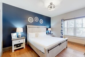 A bedroom with a bed, bedside tables, decorative wall art, a window with blinds, and a ceiling light. - Stylish 2BDR Condo with Summer Pool (The Blue Mountains)