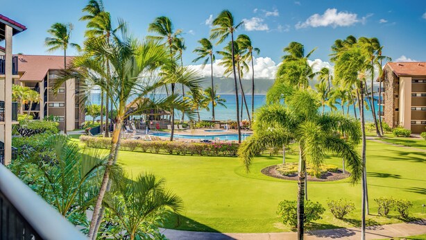 Un resort con piscina, palmeras y vista al océano.