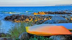 Eine felsige Küstenlinie mit einem Surfbrett und einem Kajak.