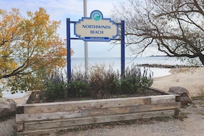A sign for Northwinds Beach with a view of the beach and ocean.