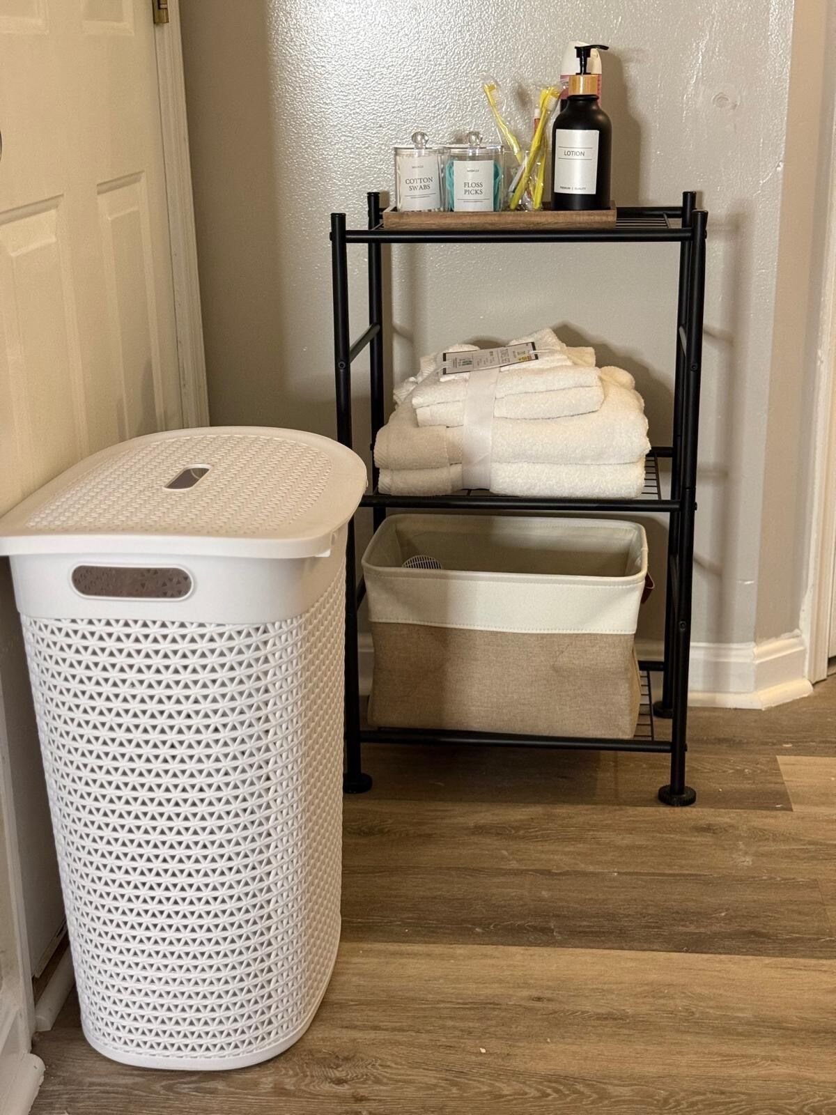 Un panier à linge, une étagère avec des articles de toilette et des serviettes pliées.