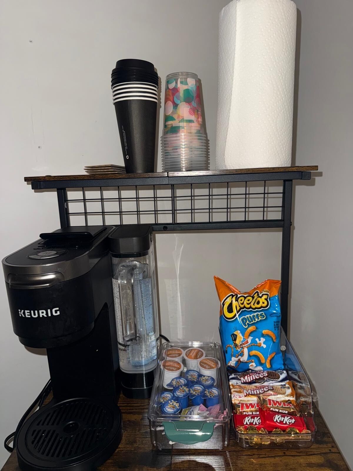 Una kitchenette con una cafetera Keurig, una licuadora, un dispensador de toallas de papel y recipientes para snacks.