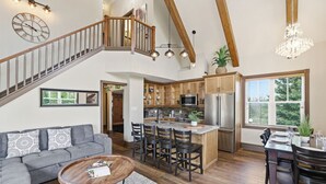 Een ruime woonkamer met een trap, een keuken met moderne apparatuur, en een eethoek.