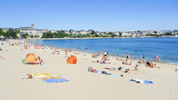 Ein Strand mit Zelten, Menschen und blauem Himmel.