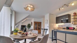Eine moderne Küche mit Einbauofen, ein Essbereich mit rundem Tisch und Stühlen sowie eine Deckenleuchte.