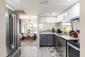 A modern kitchen with a built-in oven, a coffee maker, and a sink. - Bright Wintergreen Condo w/ Private Sauna & Golf (The Blue Mountains)
