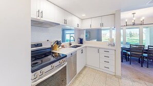 Una cucina moderna con mobili bianchi, un piano cottura e un'area pranzo con vista.