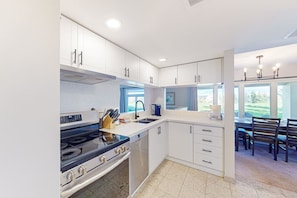 A modern kitchen with white cabinets, a stove, and a dining area with a view. - Relaxing Wintergreen Home | Golf/Mins to Blue (The Blue Mountains)