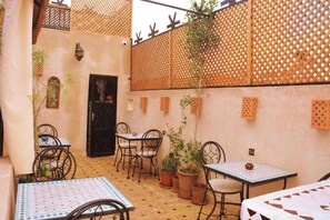 Un patio con mobiliario exterior, plantas en macetas y un muro decorativo.