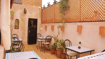 Un patio con una zona de estar, una puerta y un muro con paneles decorativos.