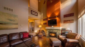 A spacious living room with leather sofas, a fireplace, a flat-screen TV, and a large painting on the wall. - Ground Floor Home, Steps to Blue Mtn Village (The Blue Mountains)