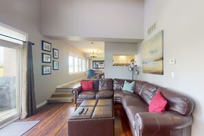 A spacious living room with a large sectional sofa, a dining area in the background, and a view through a large window. - Ground Floor Home, Steps to Blue Mtn Village (The Blue Mountains)