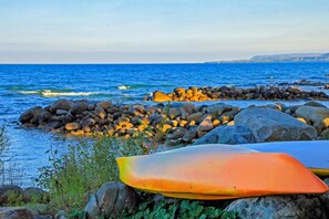 Eine felsige Küstenlinie mit Surfbrettern und Blick auf den Ozean.