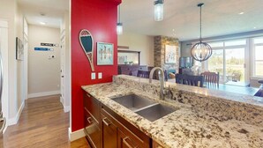 A kitchen with granite countertops, stainless steel sinks, and a red accent wall. - The Links at Rivergrass: Pool/Village Access (The Blue Mountains)