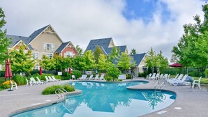 A swimming pool with lounge chairs and a shallow area marked, surrounded by houses and trees. - The Links at Rivergrass: Pool/Village Access (The Blue Mountains)