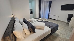 Une chambre d’hôtel moderne équipée d’un lit, d’un bureau, d’une chaise, d’une télévision et d’une fenêtre avec des rideaux.