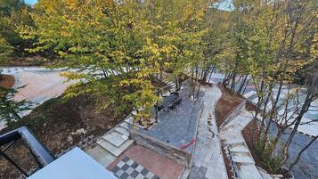 A paved outdoor area with a checkered pattern, a table with chairs, and trees with yellow leaves.
