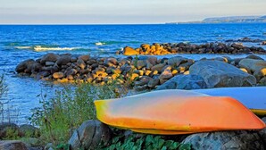 Eine felsige Küstenlinie mit Surfbrettern und Blick auf den Ozean.