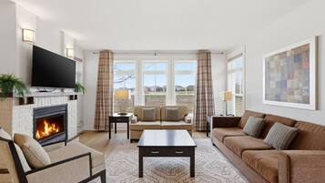 A living room with a fireplace, sofa, coffee table, and a television.