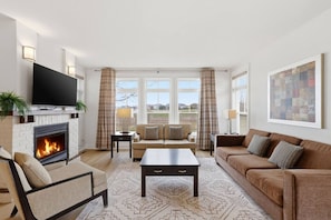 Ein Wohnzimmer mit Kamin, Sofa, Couchtisch und Fernseher.