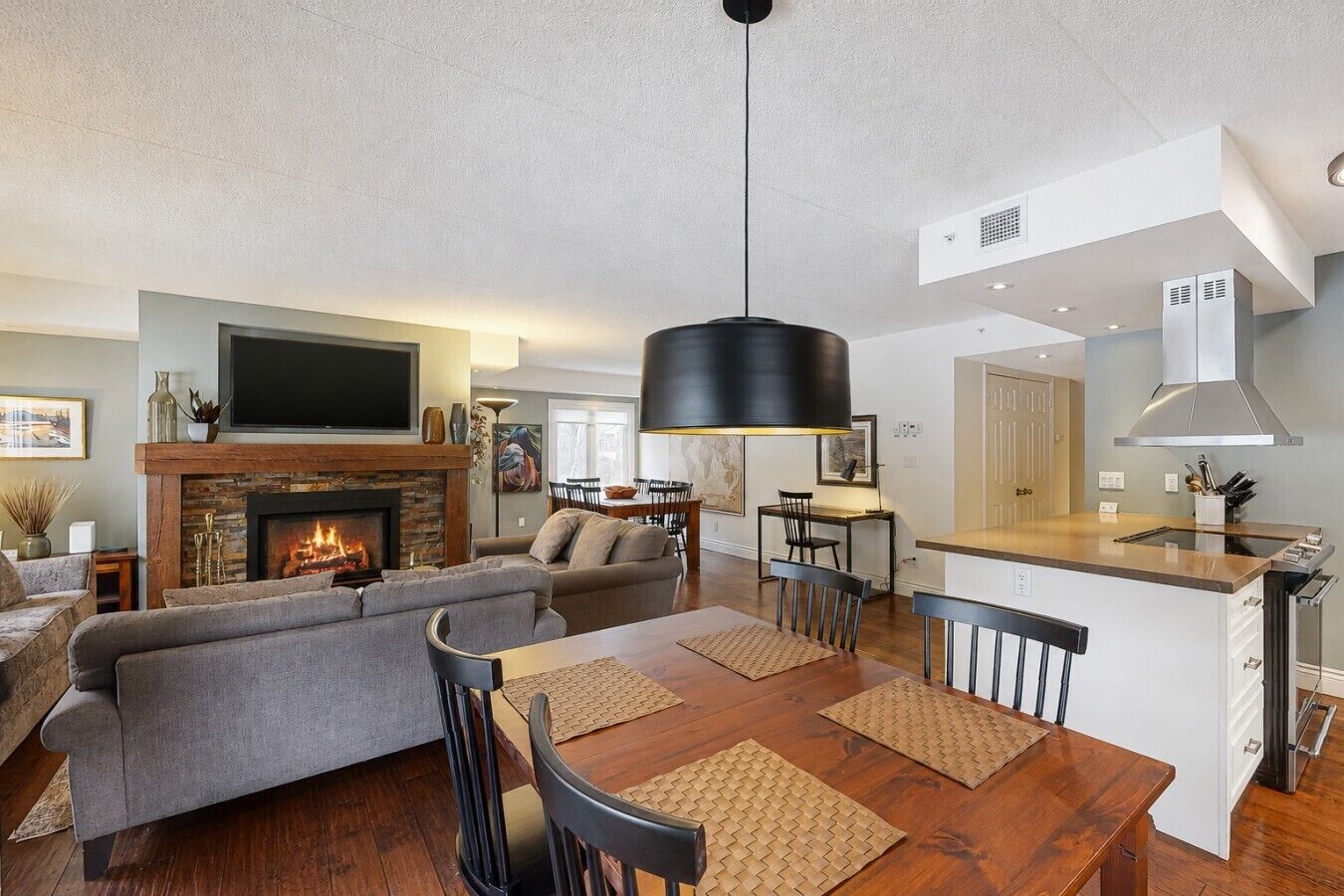 Una sala de estar moderna con chimenea, comedor y cocina con barra.