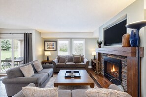 A living room with a fireplace, two sofas, a coffee table, and a television. - Spacious Mountain Walk Home, Steps to Blue! (The Blue Mountains)