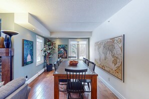 A dining area with a long table, chairs, a potted plant, and artwork on the walls. - Spacious Mountain Walk Home, Steps to Blue! (The Blue Mountains)