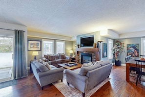 A living room with a fireplace, sofa, and dining area. - Spacious Mountain Walk Home, Steps to Blue! (The Blue Mountains)