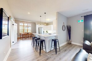 Une cuisine moderne dotée d’un îlot central, de tabourets de bar et d’un coin repas avec des chaises.