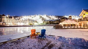 Un hotel sul lungomare con un ponte coperto di neve, due sedie e edifici illuminati sullo sfondo.