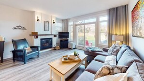 Ein modernes Wohnzimmer mit Kamin, einer Couch, einem Couchtisch und einem Fernseher.