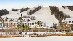 Uma pousada com vários edifícios, uma pista de esqui e uma paisagem coberta de neve.