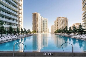 A swimming pool surrounded by high-rise buildings, with lounge chairs and trees. - Brickell High-Floor Condo w/ Views l Icon Tower 3 (Miami)