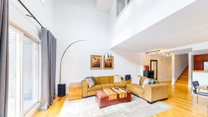 Un salón amplio con sofá modular, una mesa de centro y un ventanal con cortinas.
