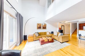 A spacious living room with a sectional sofa, a coffee table, and a large window with curtains.