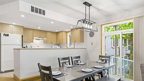 A modern kitchen with wooden cabinets, a central island, and a dining area with a table set for four. - 3 Bedroom Home | Steps to Blue Mtn Village (The Blue Mountains)