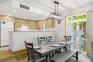 Una cocina moderna con armarios de madera, una isla central y un comedor con mesa para cuatro.