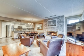 A modern living room with leather sofas, a dining area, a kitchen, and a fireplace.