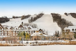 Un centro de esquí con un edificio grande, pistas de esquí y un paisaje cubierto de nieve.