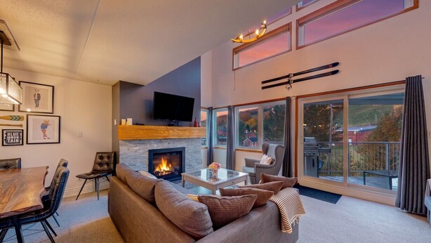 Ein modernes Wohnzimmer mit Kamin, Fernseher und Essbereich mit Stühlen und Tisch.
