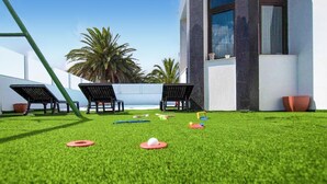 A grassy outdoor area with two lounge chairs and a building with large windows. - Stunning home in Tahiche with private swimming pool, can be inside or outside (Tahiche)