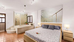 A bedroom with a large bed, a bathroom with a bathtub, and a view of a rope bridge. - Stunning home in Tahiche with private swimming pool, can be inside or outside (Tahiche)