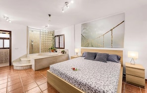 A bedroom with a large bed, a bathroom with a bathtub, and a view of a rope bridge. - Stunning home in Tahiche with private swimming pool, can be inside or outside (Tahiche)
