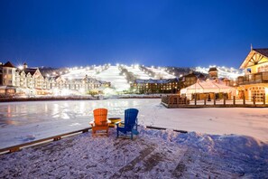 A snow-covered waterfront with two chairs and a tent, surrounded by illuminated buildings. - Mountain Loft Magic: Pool, Hot Tub, Tennis (The Blue Mountains)