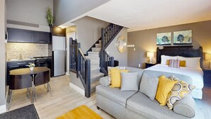 A modern apartment with a kitchen, dining area, staircase, and a bedroom with a bed and nightstands. - The Adventure Pad: Pool, Hot Tub, Tennis! (The Blue Mountains)