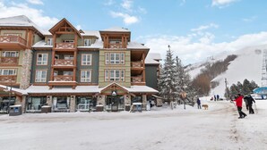A multi-story lodge with a ski lift in the background. - The Adventure Pad: Pool, Hot Tub, Tennis! (The Blue Mountains)