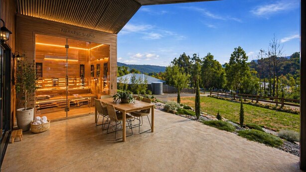 A spa with wooden architecture, a seating area, and a view of a green landscape.