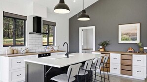 A modern kitchen with a central island, bar stools, and pendant lighting.