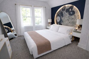 Ein Schlafzimmer mit einem großen Bett, einer runden Wanddekoration, einem Spiegel und einem Fenster mit Vorhängen.